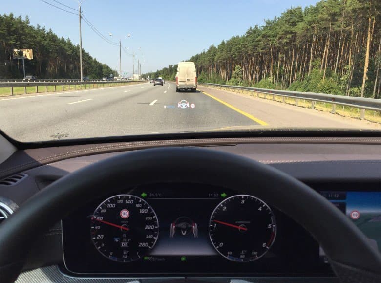 На приборной панели и проекционном дисплее видна индикация о необходимости вернуть руки на рулевое колесо